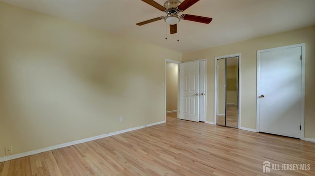 1487 Columbia Dr, North Brunswick, NJ 08902 - unfurnished bedroom with multiple closets, baseboards, light wood-style flooring, and a ceiling fan
