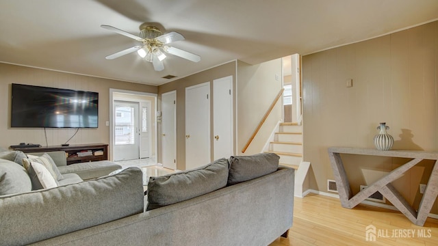 living area featuring light wood finished floors, stairway, ceiling fan, and baseboards