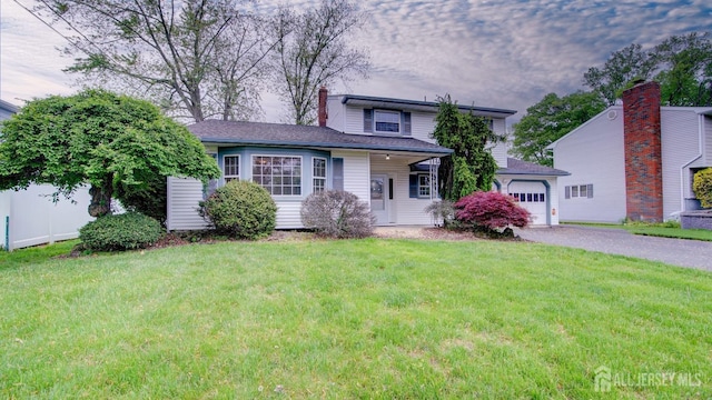 split level home featuring aphalt driveway, an attached garage, a chimney, and a front yard