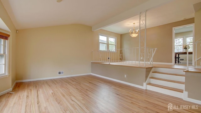 unfurnished room featuring a chandelier, wood finished floors, and baseboards