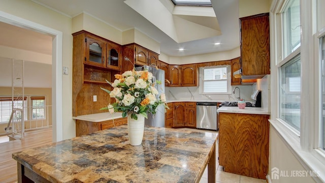 kitchen featuring stainless steel appliances, brown cabinetry, backsplash, light countertops, and ornamental molding