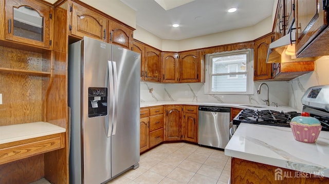 kitchen featuring a sink, stainless steel appliances, light countertops, and brown cabinets