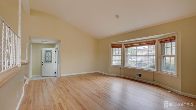 empty room with baseboards, visible vents, wood finished floors, and lofted ceiling