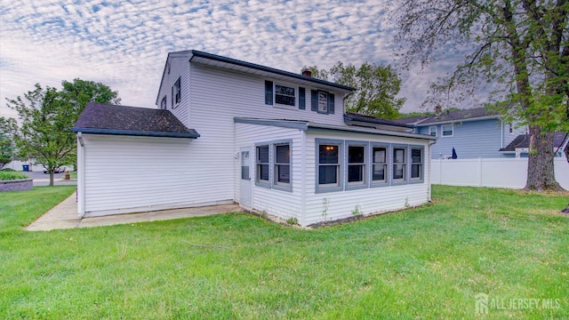 rear view of property with fence and a lawn