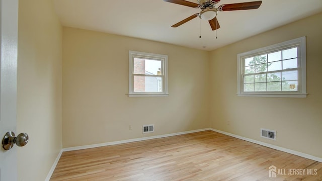 unfurnished room featuring plenty of natural light, wood finished floors, and baseboards