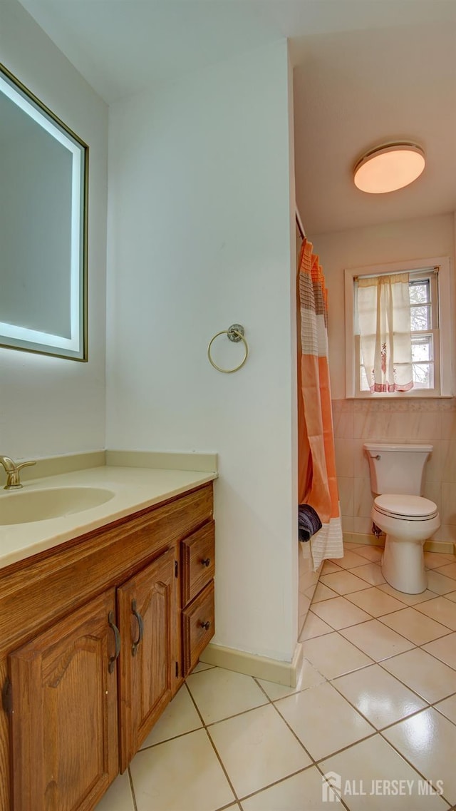 bathroom with vanity, toilet, tile walls, and tile patterned floors