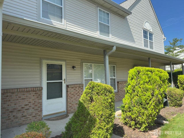 16 Sassafras Ct, North Brunswick, NJ 08902 - doorway to property featuring covered porch and brick siding