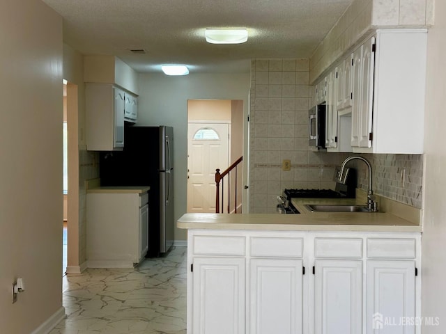 16 Sassafras Ct, North Brunswick, NJ 08902 - kitchen featuring appliances with stainless steel finishes, decorative backsplash, light marble finish flooring, white cabinets, and a textured ceiling