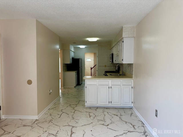 16 Sassafras Ct, North Brunswick, NJ 08902 - kitchen with light marble finish floors, white cabinets, tasteful backsplash, a textured ceiling, and light countertops