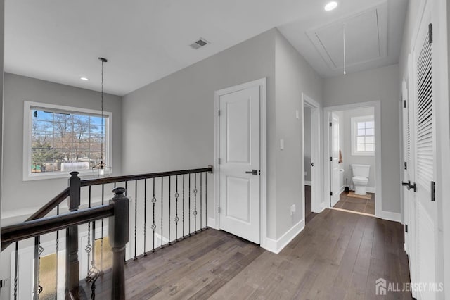 hallway featuring visible vents, baseboards, attic access, recessed lighting, and dark wood-style floors