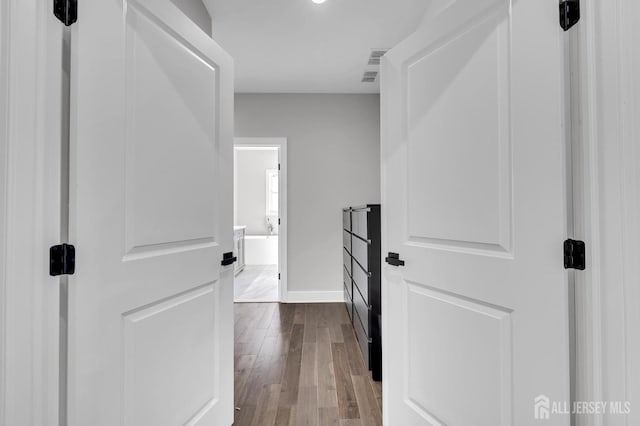 hallway with dark wood-type flooring and baseboards