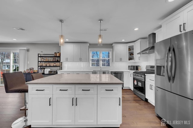 kitchen featuring visible vents, appliances with stainless steel finishes, wall chimney exhaust hood, and dark wood finished floors