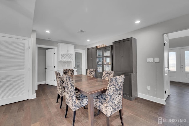 dining area with dark wood-style floors, visible vents, and baseboards