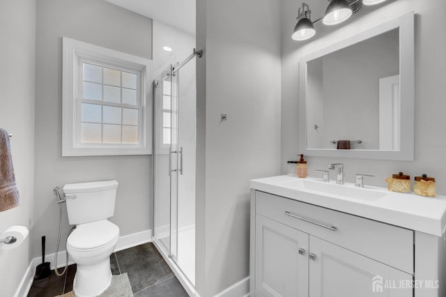 full bath with vanity, a shower stall, toilet, and baseboards