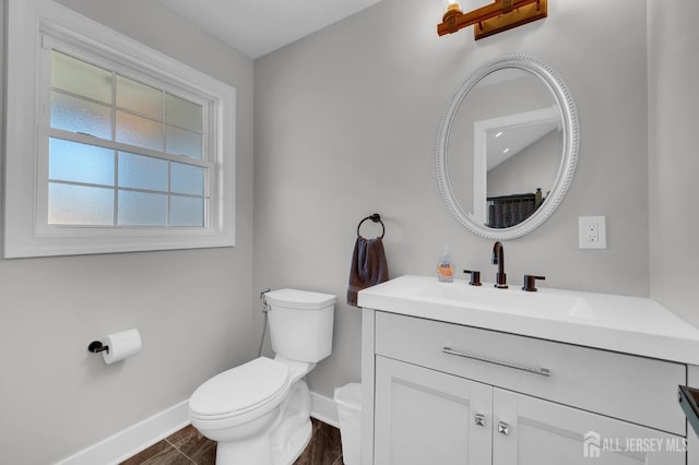 bathroom with baseboards, toilet, and vanity