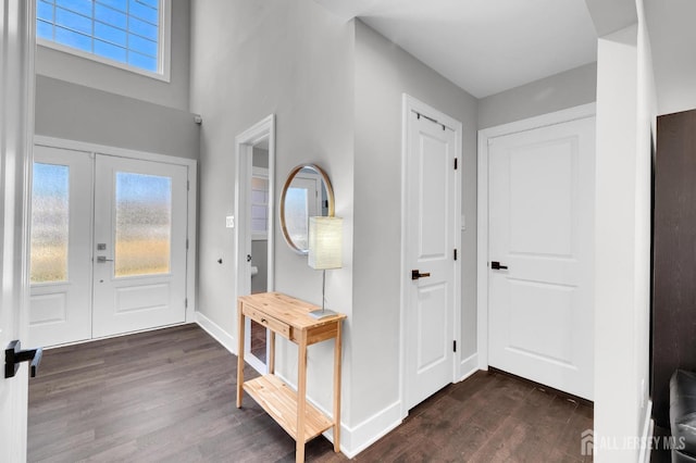 foyer entrance with dark wood-style floors, french doors, and baseboards