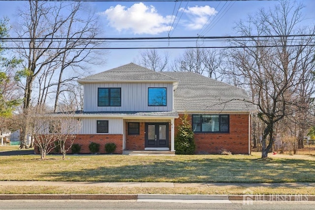 view of front of house featuring brick siding, french doors, and a front lawn