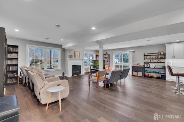 living room featuring recessed lighting, dark wood-style floors, visible vents, and ornate columns