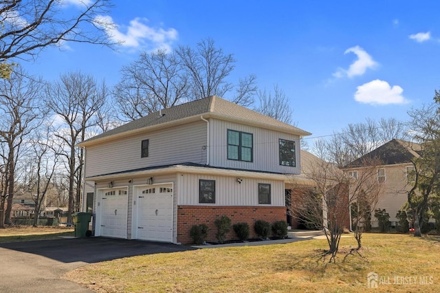 view of front facade with a front lawn, a garage, brick siding, and driveway