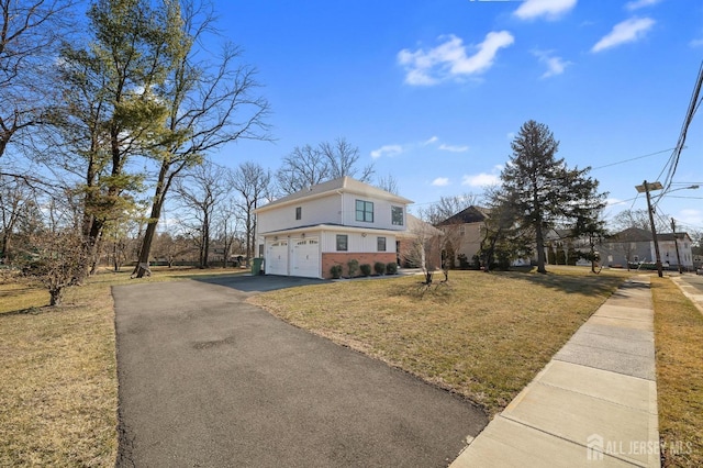 view of front of house with aphalt driveway, a front lawn, a garage, and brick siding