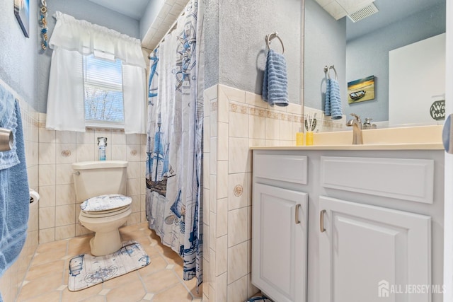 bathroom with tile patterned floors, tile walls, toilet, and visible vents