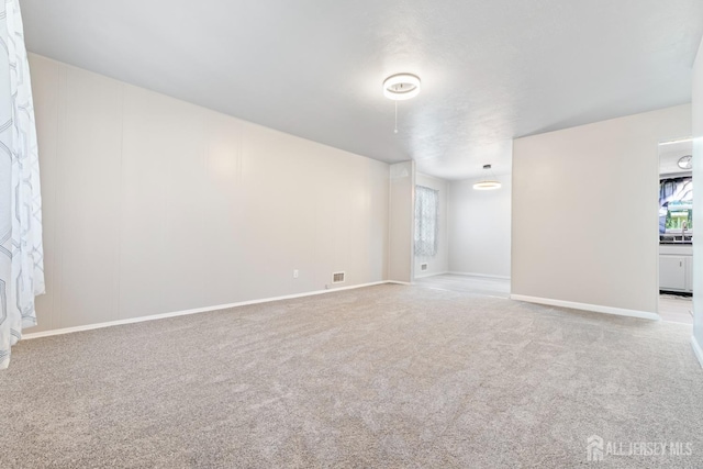 carpeted spare room featuring visible vents and baseboards