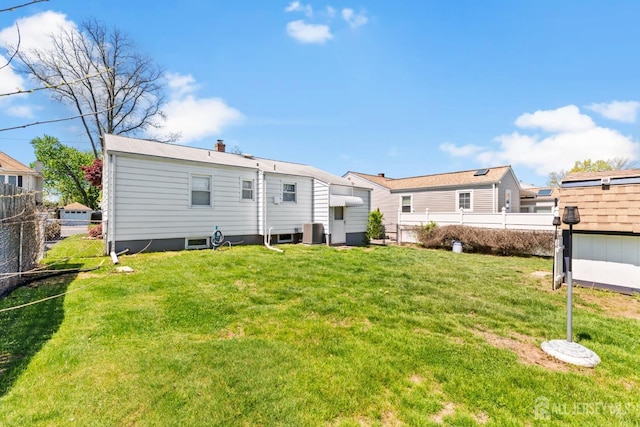back of house featuring central air condition unit, a fenced backyard, and a lawn