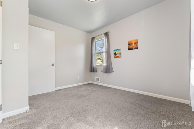 carpeted empty room featuring baseboards and visible vents