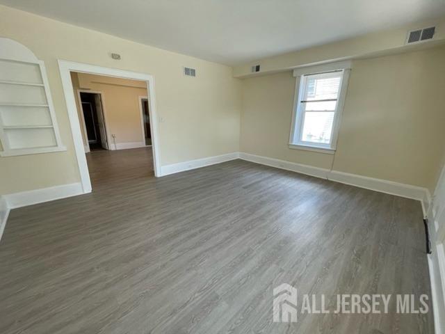 spare room featuring dark hardwood / wood-style flooring and built in features