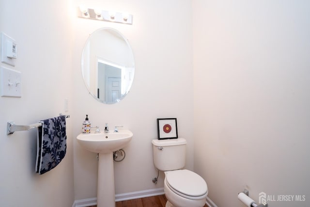 bathroom with toilet, baseboards, and wood finished floors