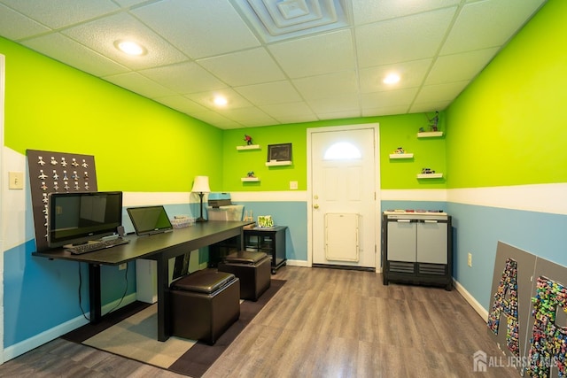 home office with wood finished floors, a paneled ceiling, and baseboards