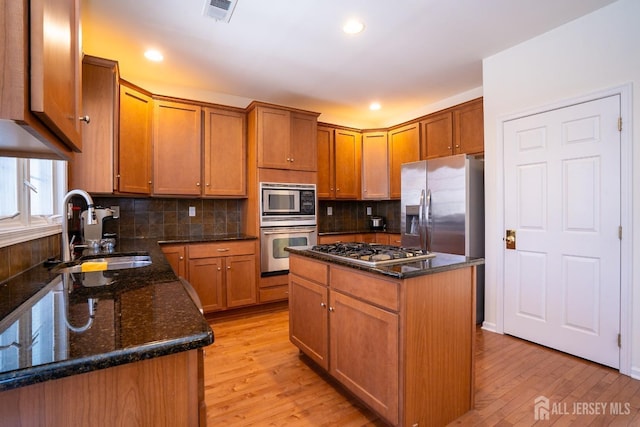 kitchen featuring stainless steel appliances, a center island, a sink, and light wood-style flooring