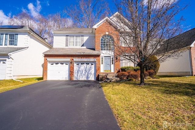 traditional-style house with a garage, a front lawn, aphalt driveway, and brick siding