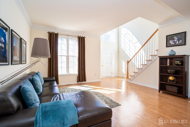 living area featuring stairs, baseboards, crown molding, and wood finished floors