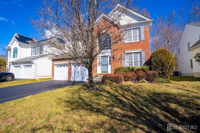 view of front of house with aphalt driveway, a front yard, brick siding, and a garage