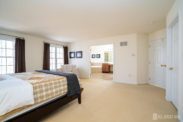 bedroom with light carpet, baseboards, visible vents, and connected bathroom