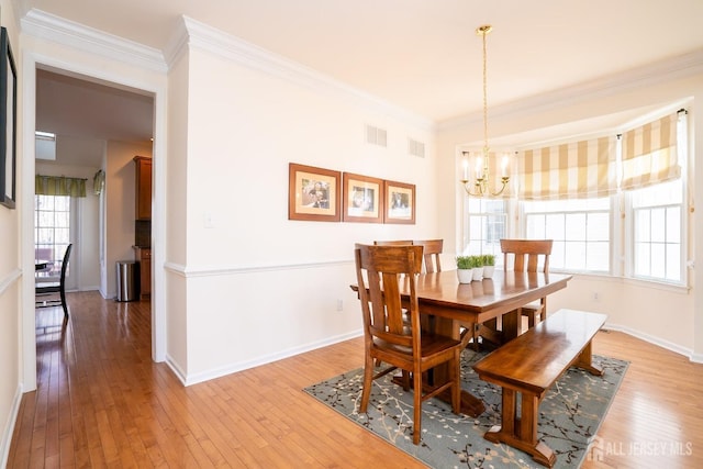 dining area featuring a chandelier, crown molding, light wood-style floors, and baseboards