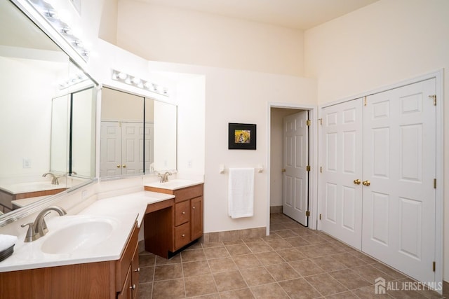 bathroom featuring tile patterned flooring, two vanities, a sink, and a high ceiling