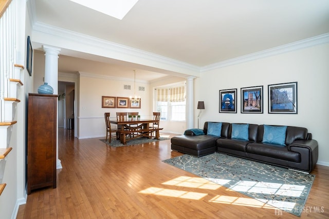 living room featuring ornamental molding, stairway, wood-type flooring, and decorative columns