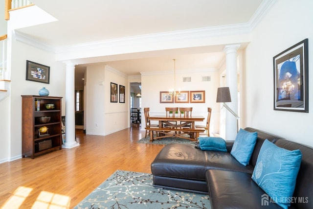 living area with crown molding, visible vents, decorative columns, and light wood finished floors