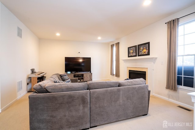 living room with a fireplace, visible vents, and light colored carpet