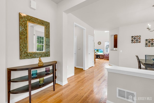 1206 Fir Ct, Franklin Twsp, NJ 08873 - corridor featuring light wood finished floors, healthy amount of natural light, and a chandelier