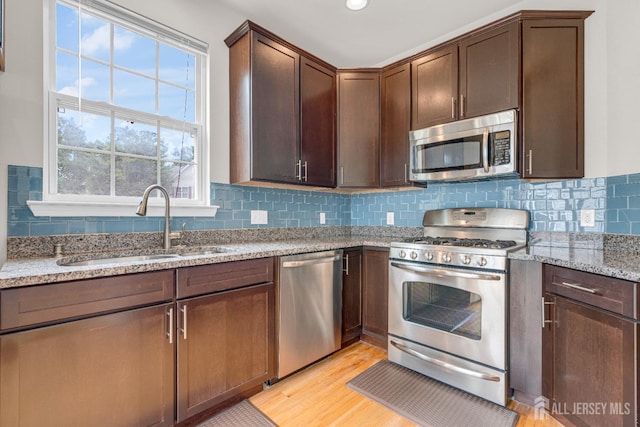 1206 Fir Ct, Franklin Twsp, NJ 08873 - kitchen featuring stainless steel appliances, light stone counters, backsplash, dark brown cabinetry, and light wood-style flooring