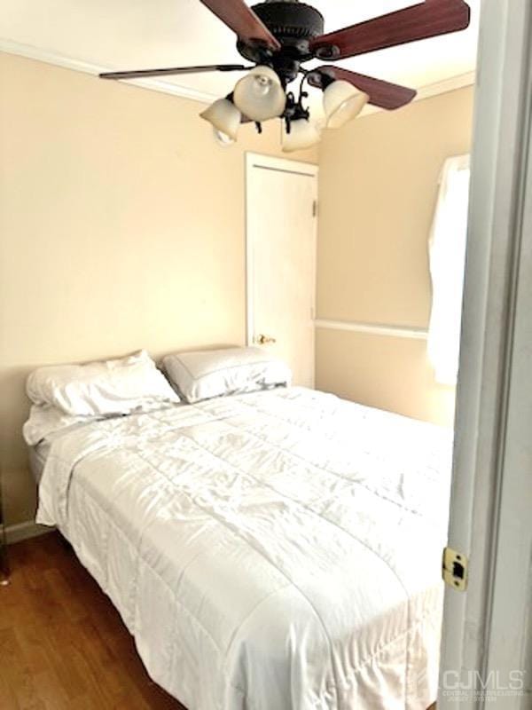 bedroom with ornamental molding, ceiling fan, and dark wood-type flooring