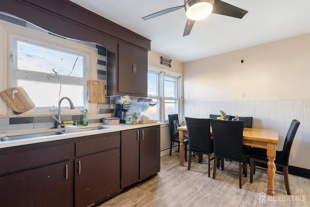 kitchen with a sink, light wood finished floors, tile walls, and light countertops