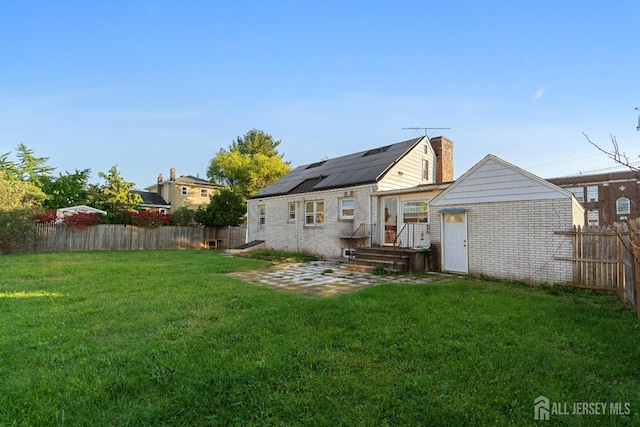 back of house with a yard, a fenced backyard, brick siding, and a chimney