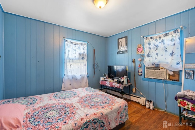 bedroom with cooling unit and wood finished floors