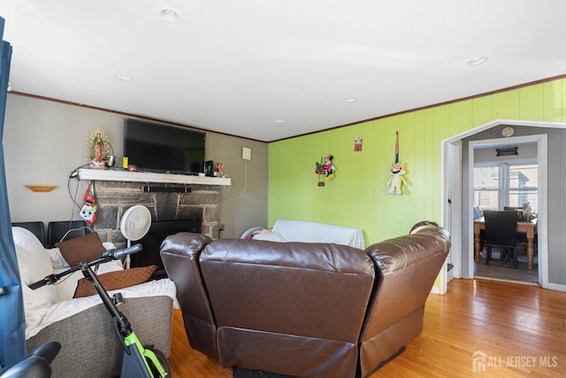 living room featuring a fireplace, crown molding, and wood finished floors