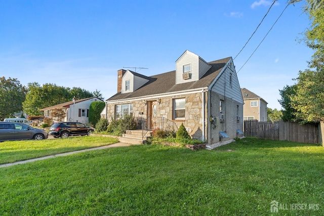 new england style home with stone siding, a front yard, and fence