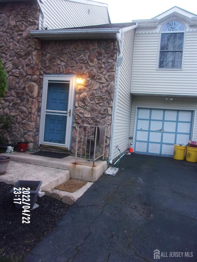 29 Jeffrey Cir S, Brunswick, NJ 08810 - doorway to property featuring stone siding, an attached garage, and asphalt driveway